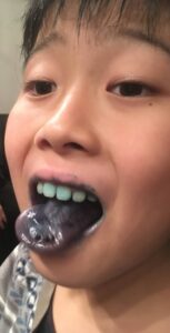 男の子が綿あめを食べて青くなった舌を出している面白い写真